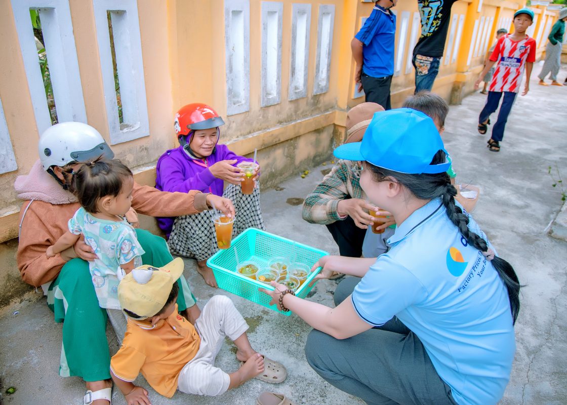 Qualitex team member handing out cold drinks to villagers and children in Phu Tan Village